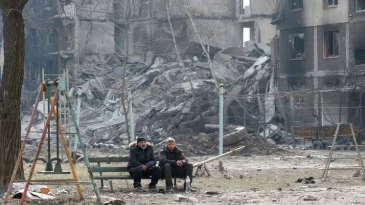 Warga Ukraina duduk di bangku di kota Mariupol yang terkepung. (Reuters)