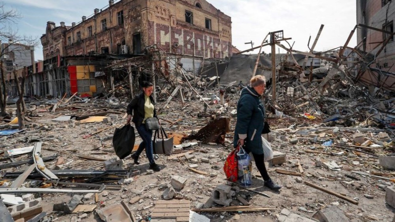 Warga membawa barang-barang mereka di dekat bangunan yang hancur akibat konflik Ukraina-Rusia, di kota pelabuhan selatan Mariupol, Ukraina 10 April 2022. (Alexander Ermochenko/Reuters)