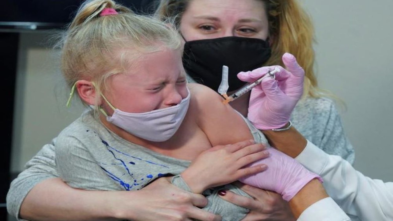 Emma Ingle (7 tahun), duduk di pangkuan ibunya Kim Obert, menerima dosis pertama vaksin Covid-19 Pfizer-BioNTech di Storrs, Connecticut, 3 November 2021. (Michelle McLoughlin/Reuters)