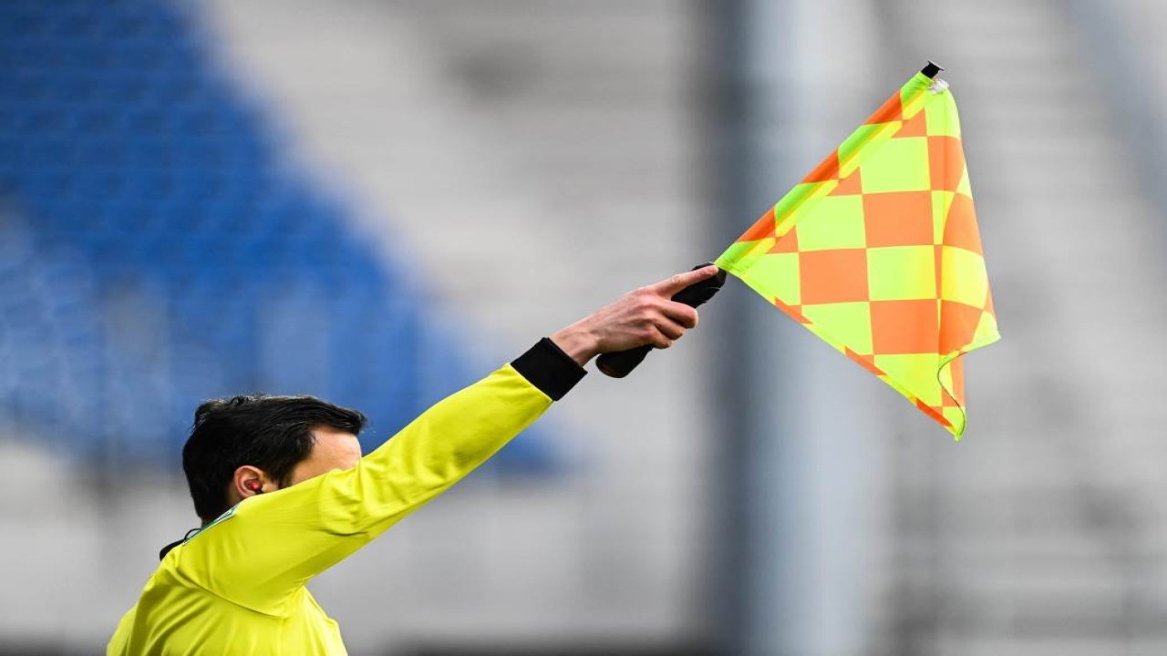 Ilustrasi wasit mengangkat bendera tanda offside/ist