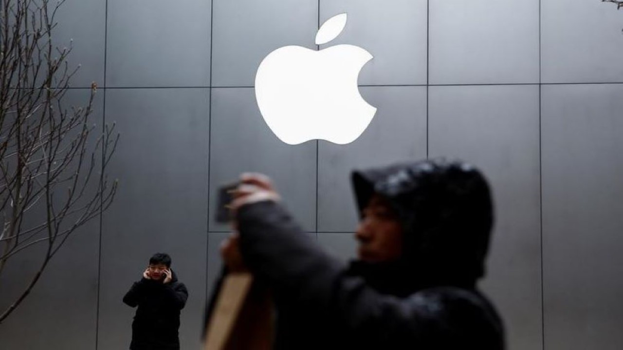 Orang-orang menggunakan ponsel mereka di luar toko Apple di Beijing, China 7 Januari 2019. (Thomas Peter/Reuters)