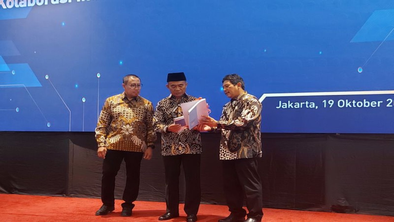 Direktur Utama BPJS Kesehatan Ghufron Mukti (kanan) saat menyerahkan buku kepada Menko PMK Muhadjir Effendy dalam Pertemuan Nasional Fasilitas Kesehatan tahun 2022, di Gedung Pusat BPJS Kesehatan, Jakarta, Rabu (19/10/2022). (ANTARA/Andi Firdaus).