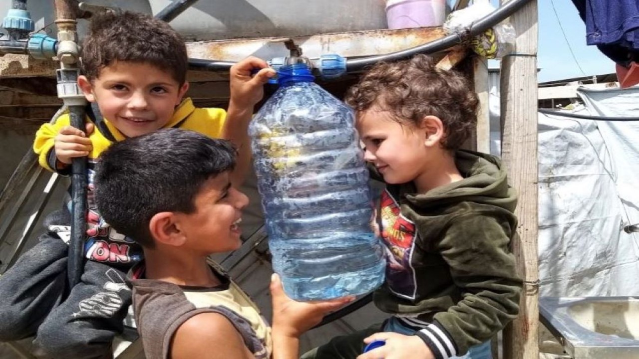 Seorang anak pengungsi Suriah memegang botol air di pemukiman tenda informal di Akkar, Lebanon. (Walid Saleh/Reuters)