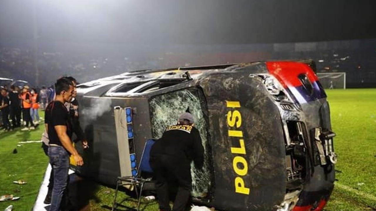 Sebuah mobil polisi terbalik akibat kericuhan usai laga Arema vs Persebaya di Stadion Kanjuruhan, Malang, Jatim, Minggu (2/10/2022). (foto: Antara)