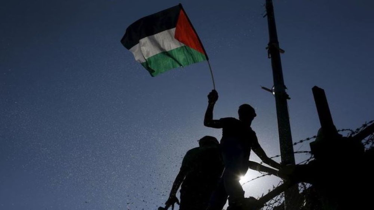 Ilustrasi. Warga mengibarkan bendera Palestina. (Reuters)