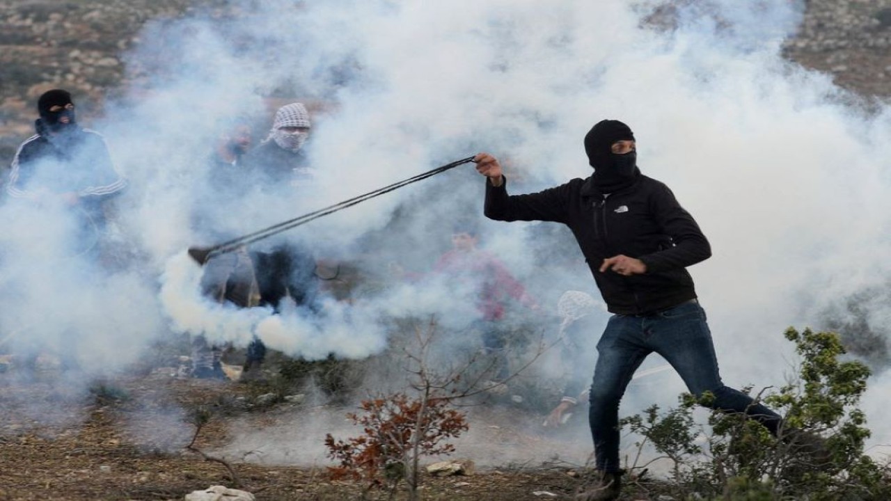 Seorang demonstran Palestina melemparkan batu selama protes terhadap pemukiman Yahudi di dekat Nablus, di Tepi Barat yang diduduki Israel pada 11 Februari 2022. (Raneen Sawafta/Reuters)