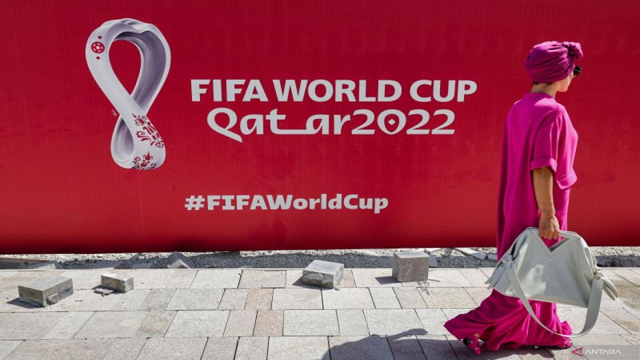 Seorang wanita berjalan di depan baliho besar logo Piala Dunia FIFA 2022 di West Bay Doha, Qatar, pada 13 Oktober 2022 (AFP/GIUSEPPE CACACE)