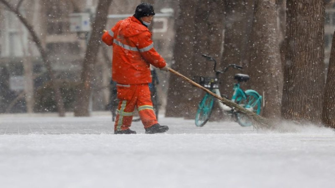 Arsip - Seorang pekerja kota menyapu salju dari jalan di Beijing, China, 20 Januari 2022. (ANTARA/REUTERS/Carlos Garcia Rawlins/as)