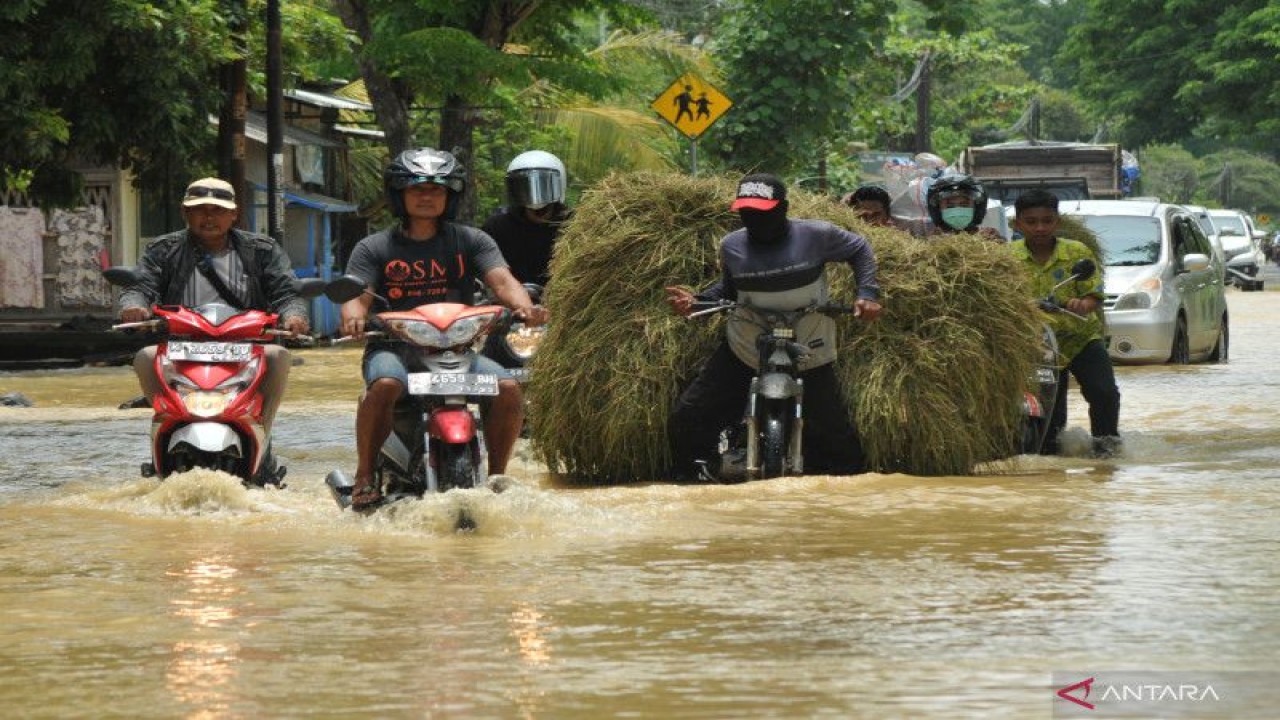 Arsip Foto. Warga melintasi jalan yang tergenang banjir di Desa Sembaturagung, Jakenan, Pati, Jawa Tengah, Sabtu (15/10/2022). (ANTARA FOTO/YUSUF NUGROHO)