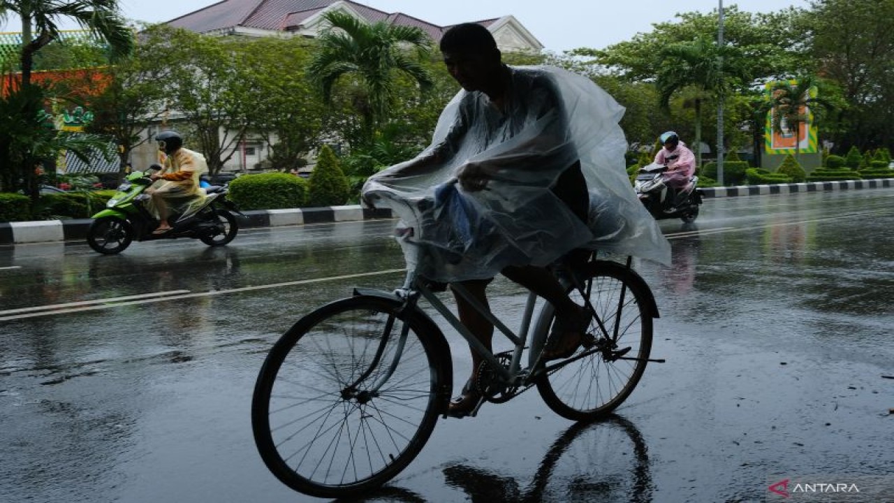 Seorang pengendara sepeda melintas saat hujan di Pontianak, Kalimantan Barat, Senin (21/11/2022). BMKG Kalbar memprakirakan terdapat potensi hujan intensitas sedang-lebat yang dapat disertai petir/angin kencang berdurasi singkat, khususnya pada kejadian hujan siang/sore dan malam hari di sebagian besar wilayah Kalimantan Barat pada 21 November dan 23-26 November 2022. ANTARA FOTO/Jessica Helena Wuysang/tom. (ANTARA FOTO/JESSICA HELENA WUYSANG)