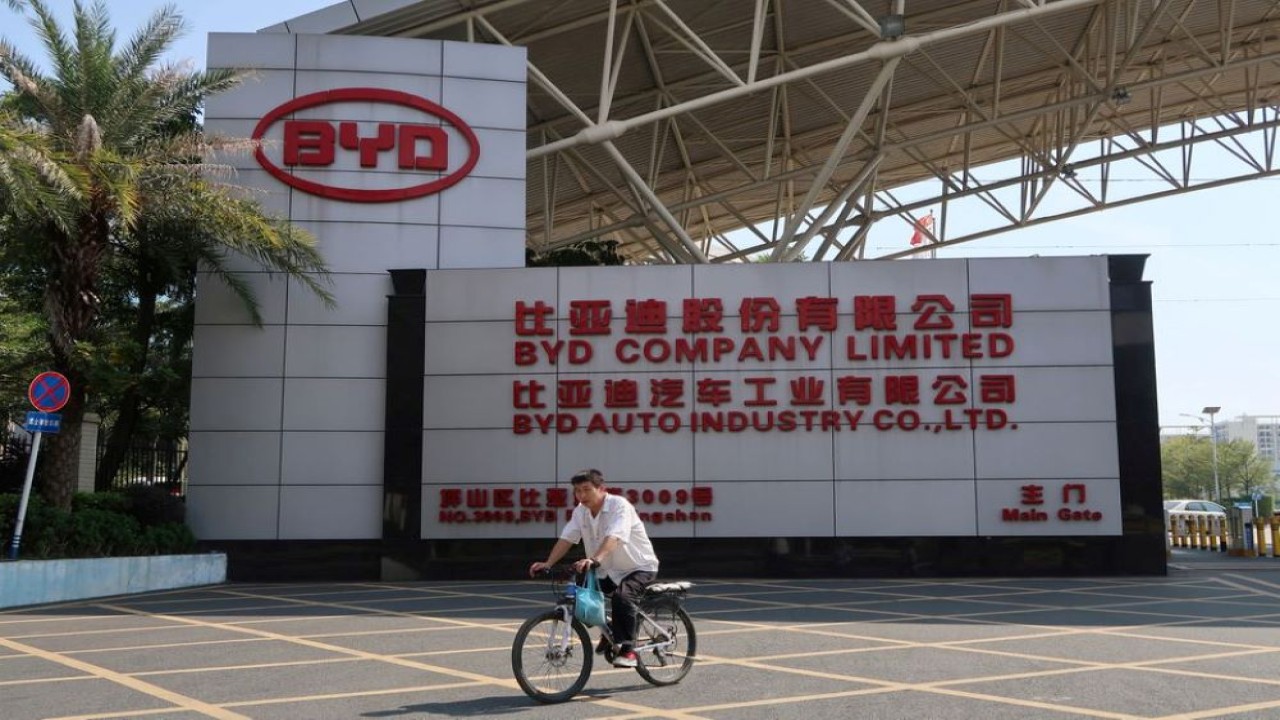 Seorang pria bersepeda melewati pintu masuk ke markas besar produsen mobil listrik China BYD di distrik Pingshan Shenzhen, Provinsi Guangdong, pada 25 Oktober 2019. (Dok/Yilei Sun/Reuters)