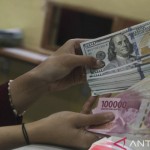 Ilustrasi: Petugas menunjukkan uang pecahan Rp100.000 dan 100 dolar AS di jasa penukaran uang asing di Jakarta. ANTARA FOTO/Rivan Awal Lingga/rwa.-1668481738
