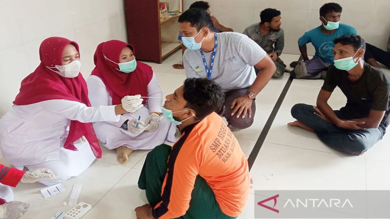 Petugas medis memeriksa kesehatan imigran etnis Rohingya di lokasi penampungan sementara di Desa Meunasah Lhok, Kecamatan Muara Batu, Kabupaten Aceh Utara. Sebanyak 110 warga Rohingya yang terdiri 72 pria dewasa dan 32 perempuan dewasa, lima anak dan seorang balita terdampar di pesisir pantai Desa Meunasah Lhok, Kecamatan Muara Batu, Kabupaten Aceh Utara pada Selasa (15/11/2022) sekitar pukul 03.25 WIB. ANTARA/Dedy Syahputra