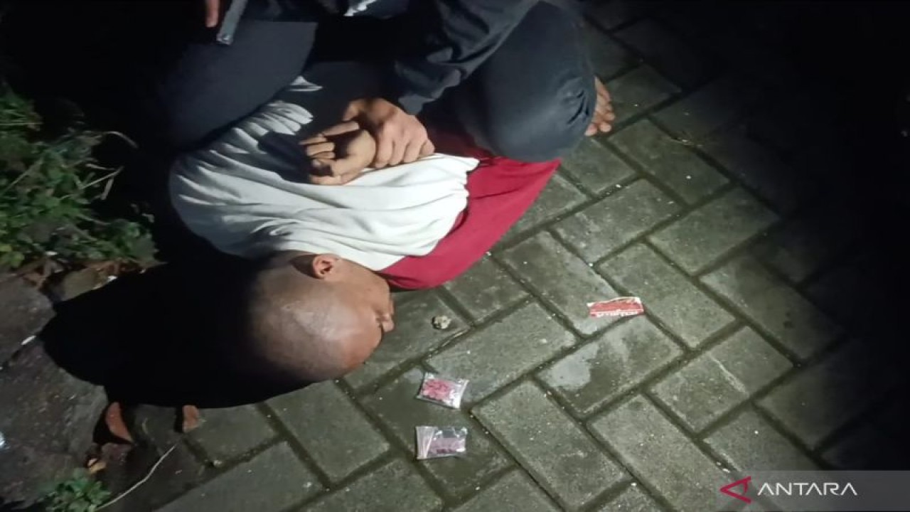 Polisi mengamankan terduga kurir peredaran narkoba berinisial MA dengan barang bukti pil ekstasi dalam penangkapan di depan ruko kawasan Dakota, Mataram, Sabtu malam (19/11/2022). (ANTARA/Dhimas B.P.)