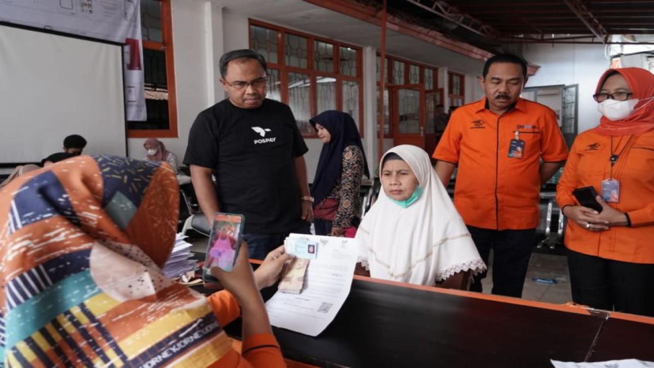 Direktur Bisnis Jasa Keuangan PT Pos Indonesia (Persero) Haris (berdiri kiri) menyaksikan petugas Kantor Pos melayani warga mengambil bantuan langsung tunai bahan bakar minyak (BLT BBM) di Cianjur, Jawa Barat Selasa (29/11/2022) (Antara/HO/Pos Indonesia)