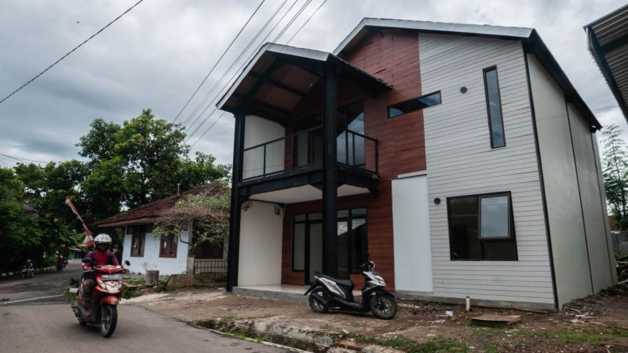 Warga melintas di depan rumah tahan gempa di Rangkasbitung, Lebak, Banten, Jumat (21/1/2022). Prototipe rumah tahan gempa yang dibangun oleh Badan Riset dan Inovasi Nasional (BRIN) tersebut dapat menahan gempa berkekuatan magnitudo 8,0. ANTARA FOTO/Muhammad Bagus Khoirunas/nym