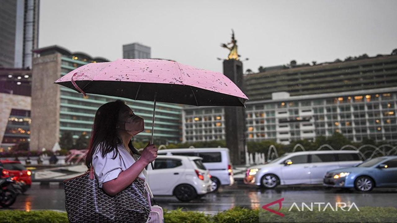 Seorang warga menggunakan payung saat turun hujan di kawasan Bundaran Hotel Indonesia, Jakarta, Selasa (4/10/2022). ANTARA FOTO/M Risyal Hidayat/tom/pri.