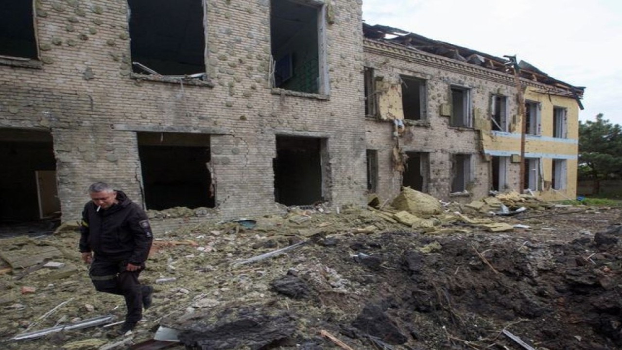 Seorang petugas polisi berjalan di sebelah gedung sekolah yang rusak akibat serangan militer Rusia, saat serangan Rusia di Ukraina berlanjut, di pemukiman Kostiantynivka, di wilayah Donetsk, Ukraina (22/5/2022). ANTARA/REUTERS/Anna Kudriavtseva/aa. (REUTERS/STRINGER)