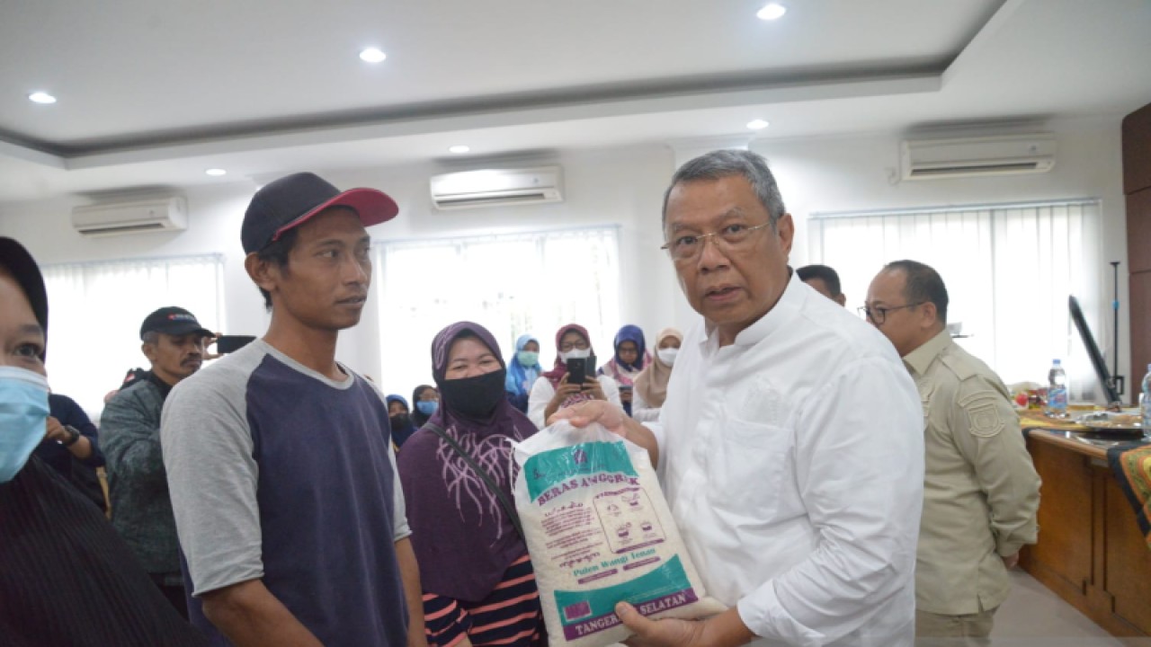 Wali Kota Tangerang Selatan Benyamin Davnie (kanan) memberikan bantuan bahan pangan kepada warga sebagai upaya pengendalian inflasi.