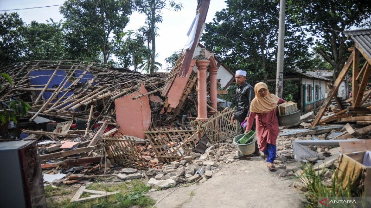 Warga melintas di depan rumah yang roboh akibat gempa di Kampung Selakawung Tengah, Kabupaten Cianjur, Jawa Barat, Selasa (22/11/2022). ANTARA FOTO/Raisan Al Farisi/pras. (ANTARA FOTO/RAISAN AL FARISI)