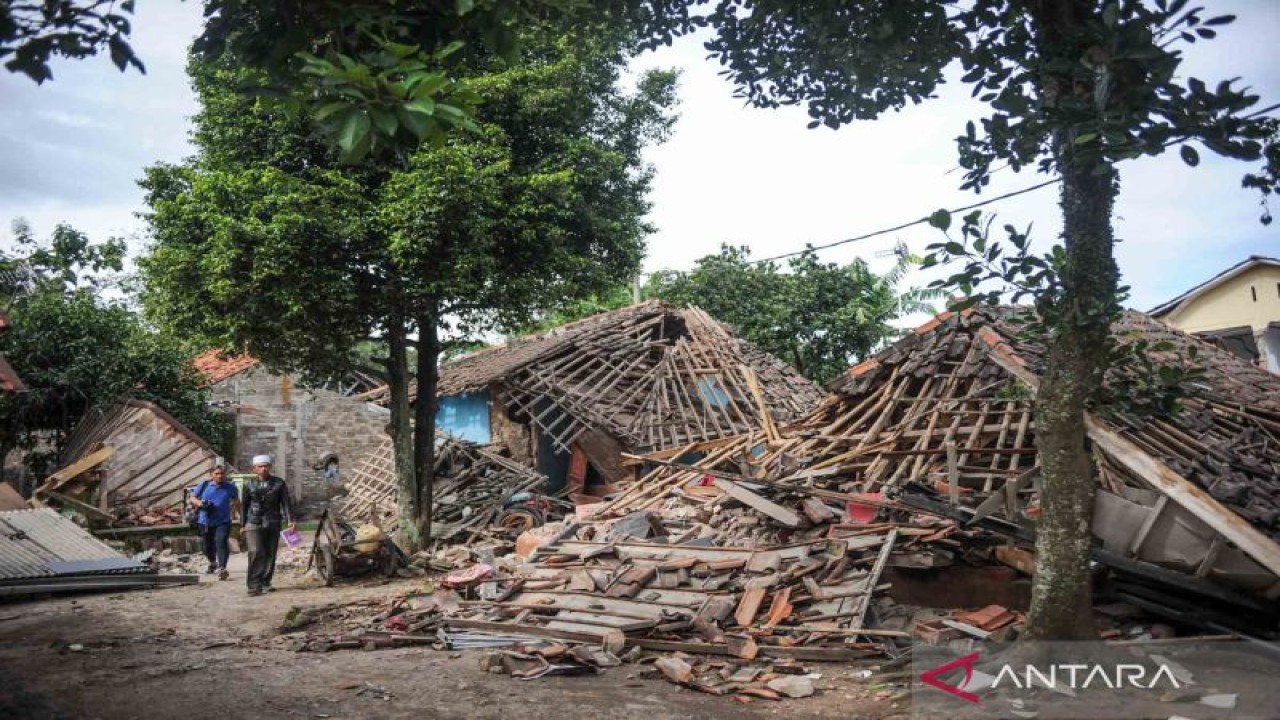 Warga melintas di depan sejumlah rumah yang roboh akibat gempa di Kampung Selakawung Tengah, Kabupaten Cianjur, Jawa Barat, Selasa (22/11/2022). (ANTARA FOTO/Raisan Al Farisi/wsj)