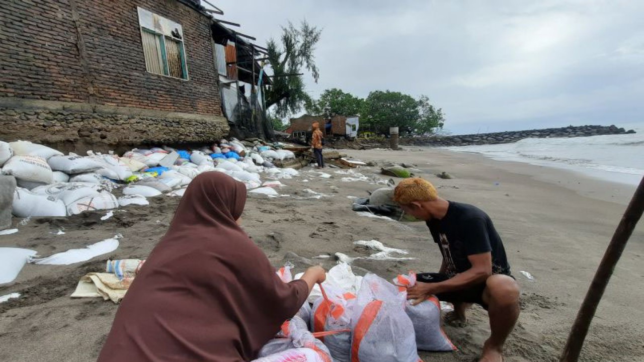 Warga Pasie Baru, Nagari Pilubang, Kecamatan Sungai Limau, Kabupaten Padang Pariaman, Sumbar sedang mengikat karung yang berisi pasir untuk membantu menahan ombak, Kamis. ANTARA/Aadiaat M. S.