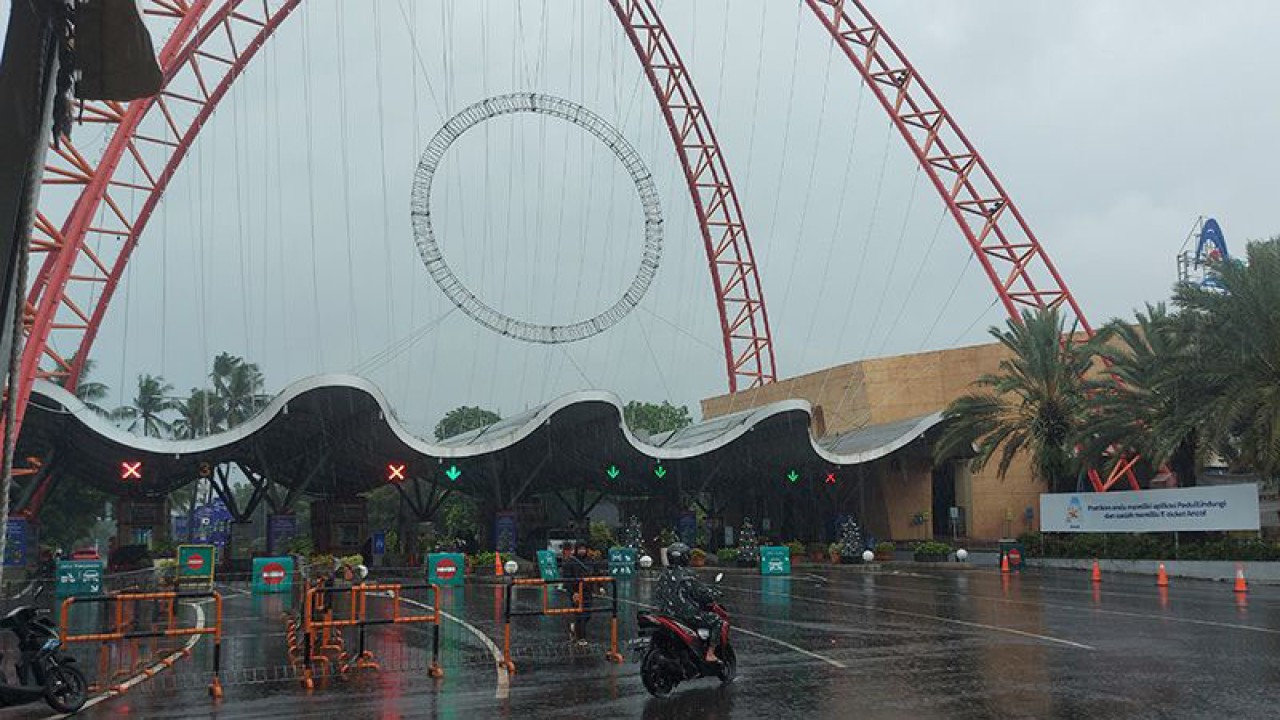 Seorang pengendara sepeda motor melintasi depan pintu gerbang barat Taman Impian Jaya Ancol saat hujan di Jakarta Utara pada Rabu (28/12/2022). ANTARA/Abdu Faisal/aa.