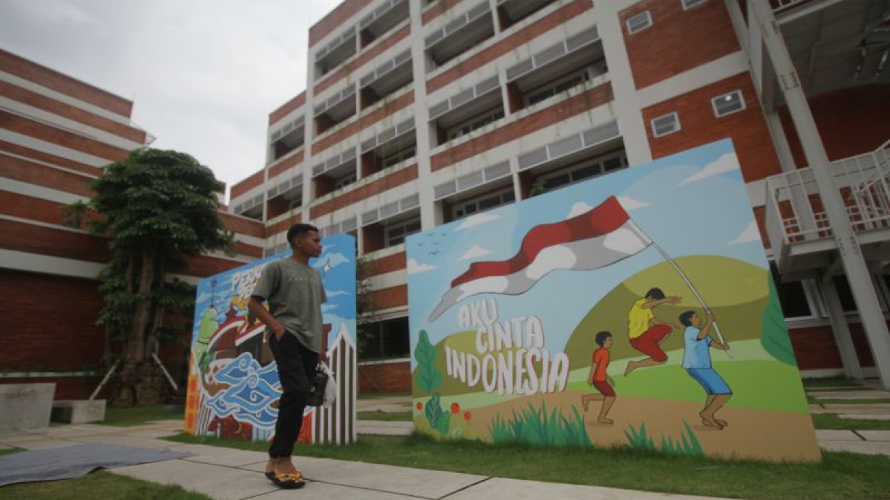 Mahasiswa melintas di samping mural di Asrama Mahasiswa Nusantara (AMN) di Surabaya, Jawa Timur, Rabu (30/11/2022). ANTARA FOTO/Zainal Arifin/ma/YU