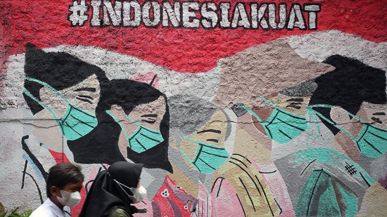 Arsip Foto. Pengendara motor melintas di depan mural edukasi pemakaian masker untuk mencegah penularan COVID-19 di Tangerang Selatan, Banten, Selasa (15/2/2022). (ANTARA FOTO/MUHAMMAD IQBAL)