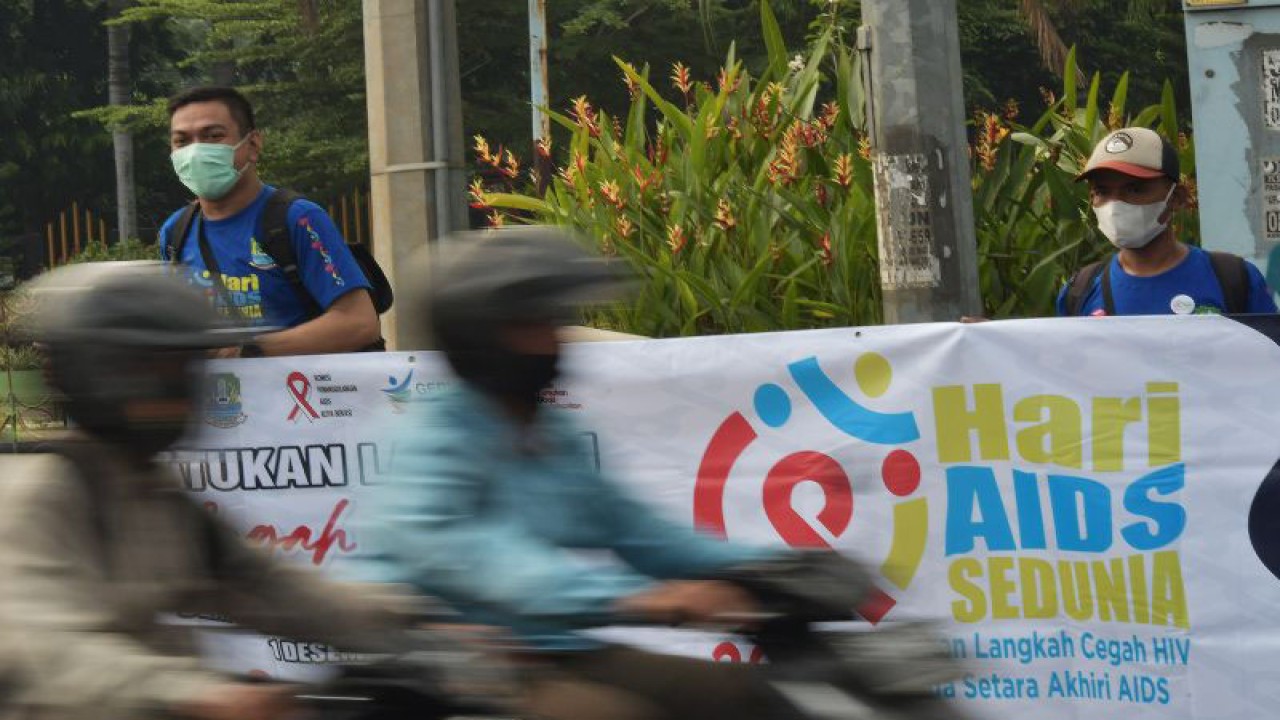 Petugas Dinas Kesehatan dan warga membentangkan spanduk saat peringatan Hari AIDS sedunia di Jalan Jenderal Ahmad Yani, Bekasi, Jawa Barat, Kamis (1/12/2022). Petugas memberikan sosialisasi kepada pengguna jalan untuk tidak mendiskriminasi orang dengan HIV / AIDS (ODHA) dan mencegah perlakuan tidak setara yang justru menghambat upaya dalam mengakhiri HIV / AIDS. ANTARA/Fakhri Hermansyah/nym