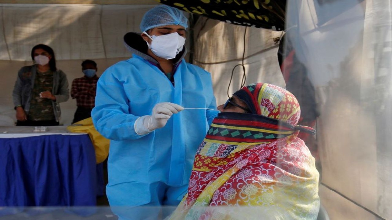 Seorang petugas kesehatan mengumpulkan sampel swab dari seorang wanita selama kampanye pengujian antigen cepat untuk penyakit virus corona (Covid-19), di Ahmedabad, India, 27 Januari 2021. (Amit Dave/Reuters)