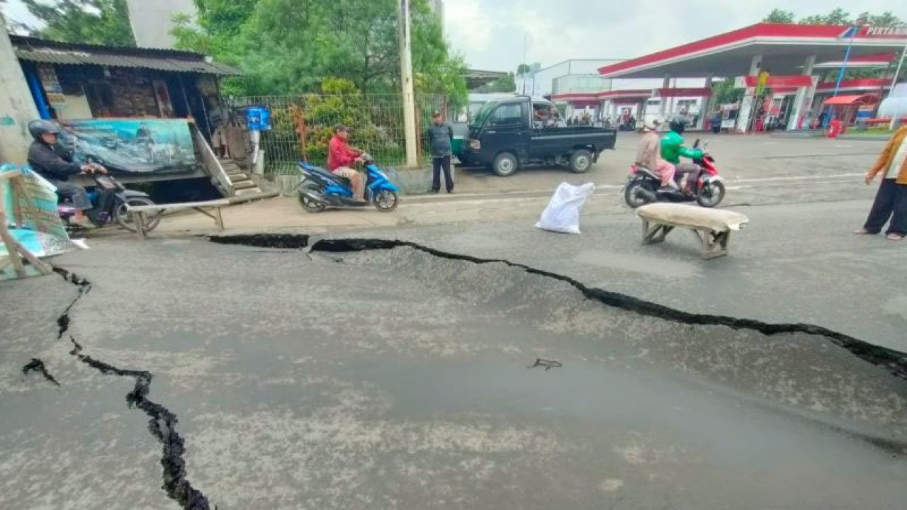 Pengendara motor melintasi jalan yang amblas di Jalan Cibolerang, Kota Bandung, Jawa Barat, Jumat (2/12/2022). (ANTARA/Bagus Ahmad Rizaldi)