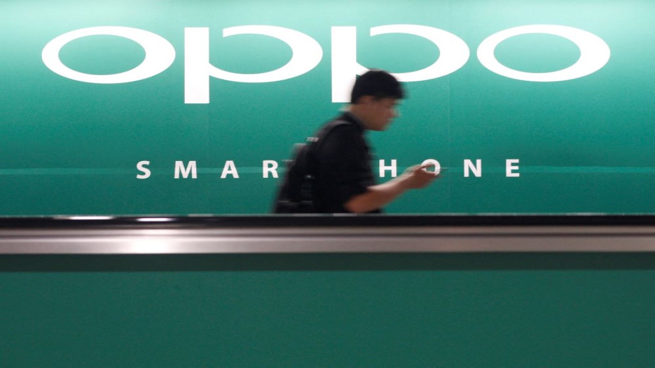 Seorang komuter menggunakan ponselnya melewati iklan produsen smartphone China Oppo di sebuah stasiun kereta api di Singapura, 8 Mei 2014. (Edgar Su/Reuters)