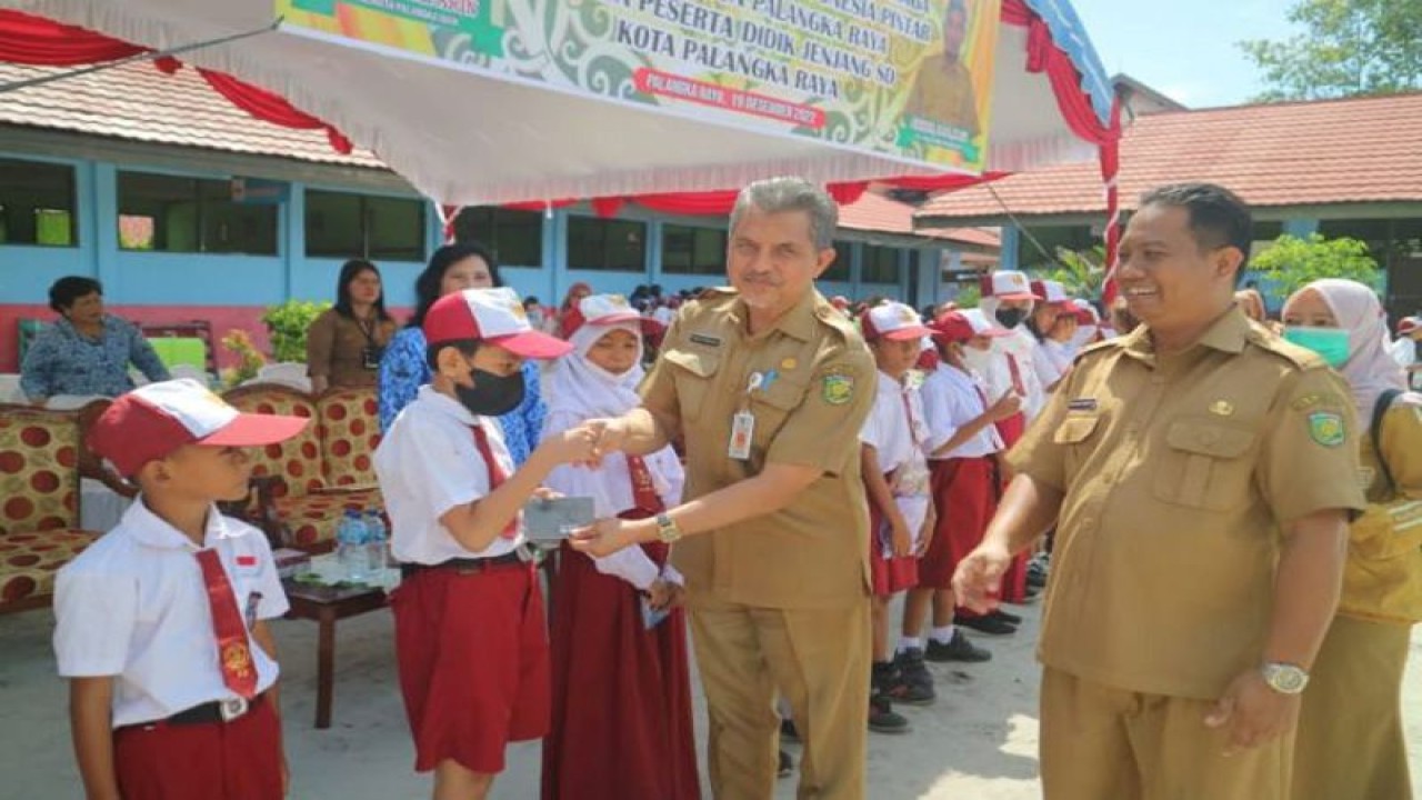 Plt Asisten Administrasi Umum Harry Maihadi didampingi pihak DIsdik Kota setempat menyerahkan secara simbolis beasiswa PIP kepada peserta didik yang berhak menerima bantuan tersebut, Senin (19/12/2022). ANTARA/HO-Disdik Kota Palangka Raya