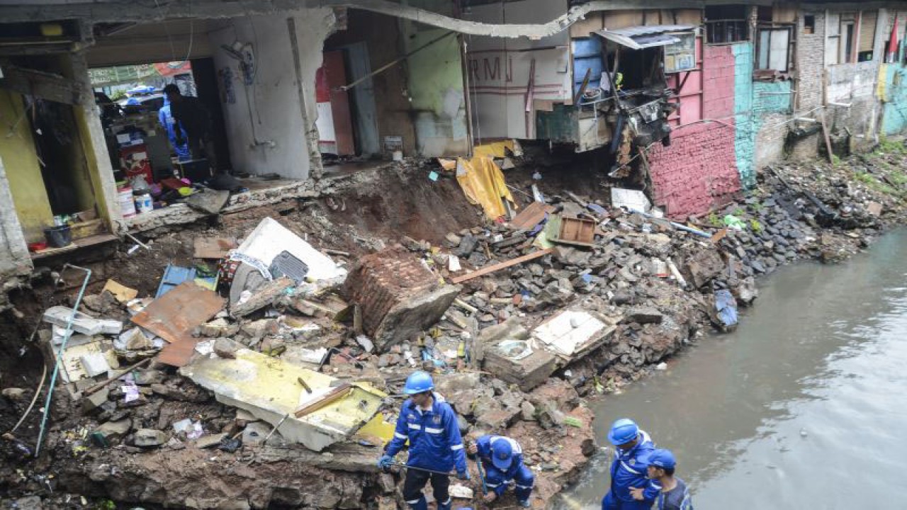 Sejumlah petugas SDA (Sumber Daya Air) merapikan material bangunan warung amblas di saluran penghubung Pulomas, Jakarta Timur, Jum'at (24/1/2020). ANTARA FOTO/ Fakhri Hermansyah/ama. ANTARA FOTO/Fakhri Hermansyah