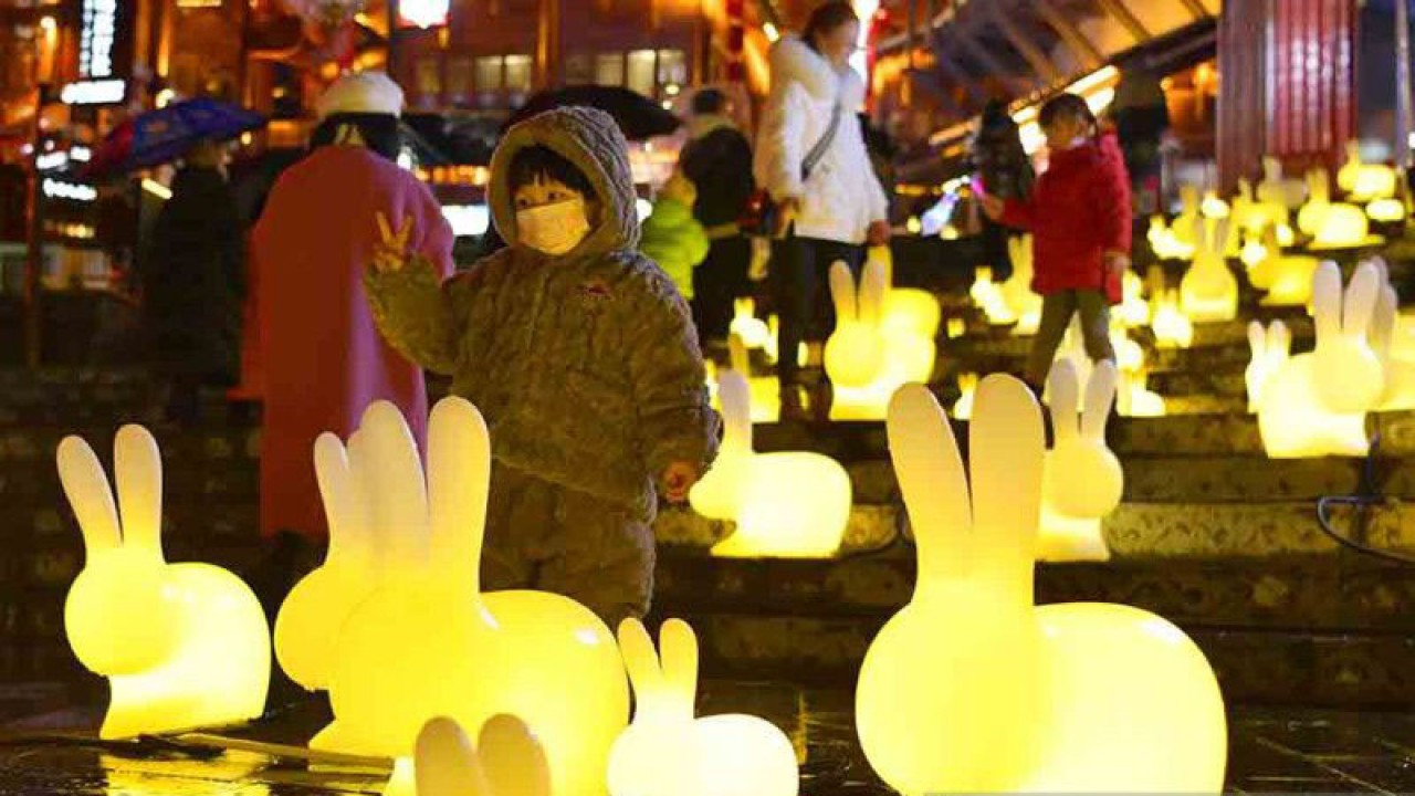 Seorang anak berpose di antara lampion-lampion berbentuk kelinci di wilayah Xuan'en, Prefektur Otonom Etnis Tujia dan Miao Enshi, Provinsi Hubei, China tengah, Minggu (15/1/2023). Menjelang Tahun Baru Imlek, yang akan menandai dimulainya Tahun Kelinci, berbagai hiasan dan kerajinan tangan yang menampilkan gambar kelinci memenuhi jalanan untuk menambah kemeriahan perayaan tersebut. ANTARA FOTO/Xinhua/Song Wen/rwa.