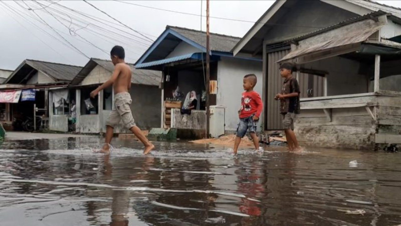 Sejumlah anak bermain di tengah banjir rob merendam kawasan pesisir Kampung Bugis, Kota Tanjungpinang, Kepri, Kamis (25/1). (Ogen)