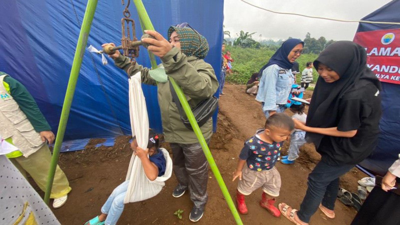 Bidan sedang mengukur berat badan anak dengan menggunakan timbangan di posyandu darurat akibat gempa bumi Cianjur Jawa Barat. (ANTARA/Hreeloita Dharma Shanti)