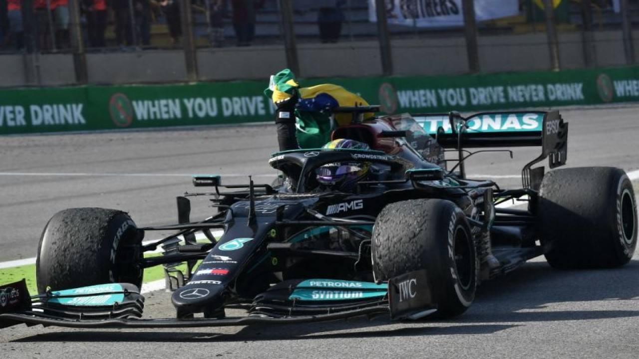 Arsip - Pebalap Mercedes Lewis Hamilton melakukan selebrasi dengan mengibarkan bendera Brasil setelah memenangi Grand Prix Sao Paulo, Autodromo Jose Carlos Pace, Interlagos. (14/11/2021) (AFP/NELSON ALMEIDA)