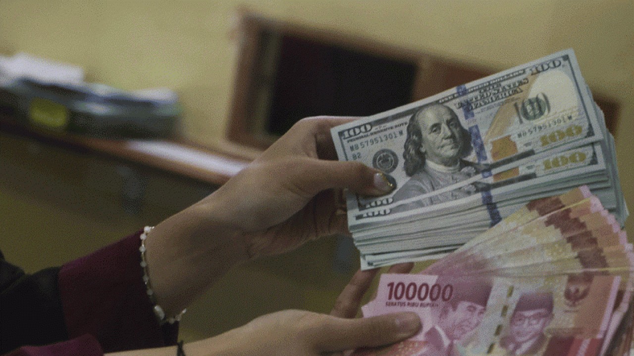 Ilustrasi: Petugas menunjukkan uang pecahan Rp100.000 dan 100 dolar AS di jasa penukaran uang asing di Jakarta. ANTARA FOTO/Rivan Awal Lingga/rwa.