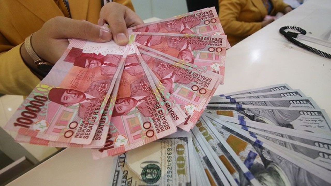 Ilustrasi: Teller bank menunjukkan uang pecahan dolar AS dan rupiah di Jakarta. ANTARA FOTO/Rivan Awal Lingga/ama.