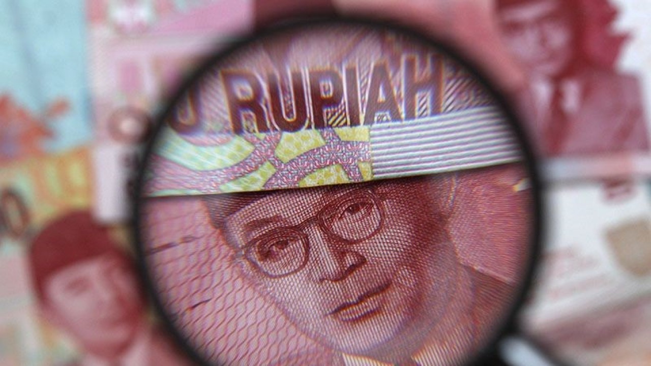Ilustrasi - Uang kertas seratus ribu rupiah terlihat melalui kaca pembesar dalam ilustrasi foto yang diambil di Singapura, 14 Maret 2013. ANTARA/REUTERS/Edgar Su/pri.