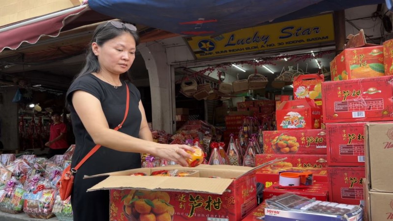 Seorang pemilik toko jeruk khas Imlek di Batam memeriksa barang dagangannya. ANTARA/Jessica