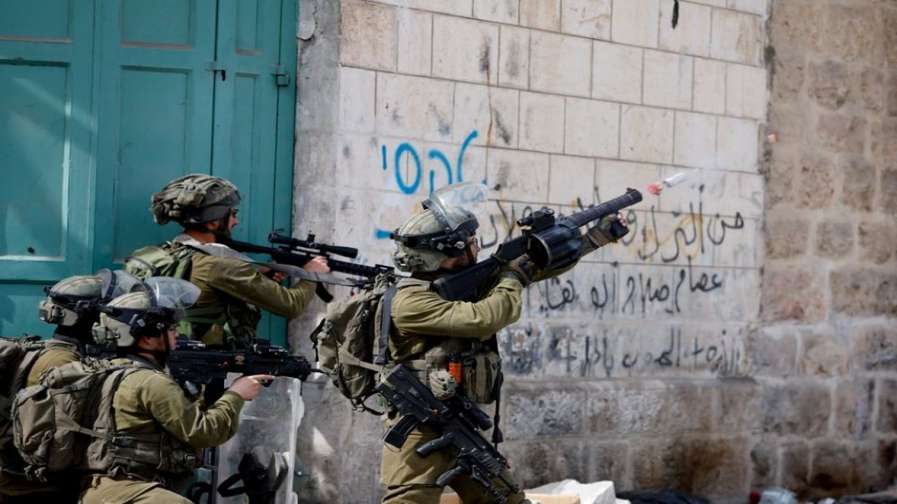 Seorang tentara Israel menggunakan senjata di tengah bentrokan dengan pengunjuk rasa Palestina, di Hebron, Tepi Barat yang diduduki Israel, 1 April 2022. (Mussa Qawasma/Reuters)