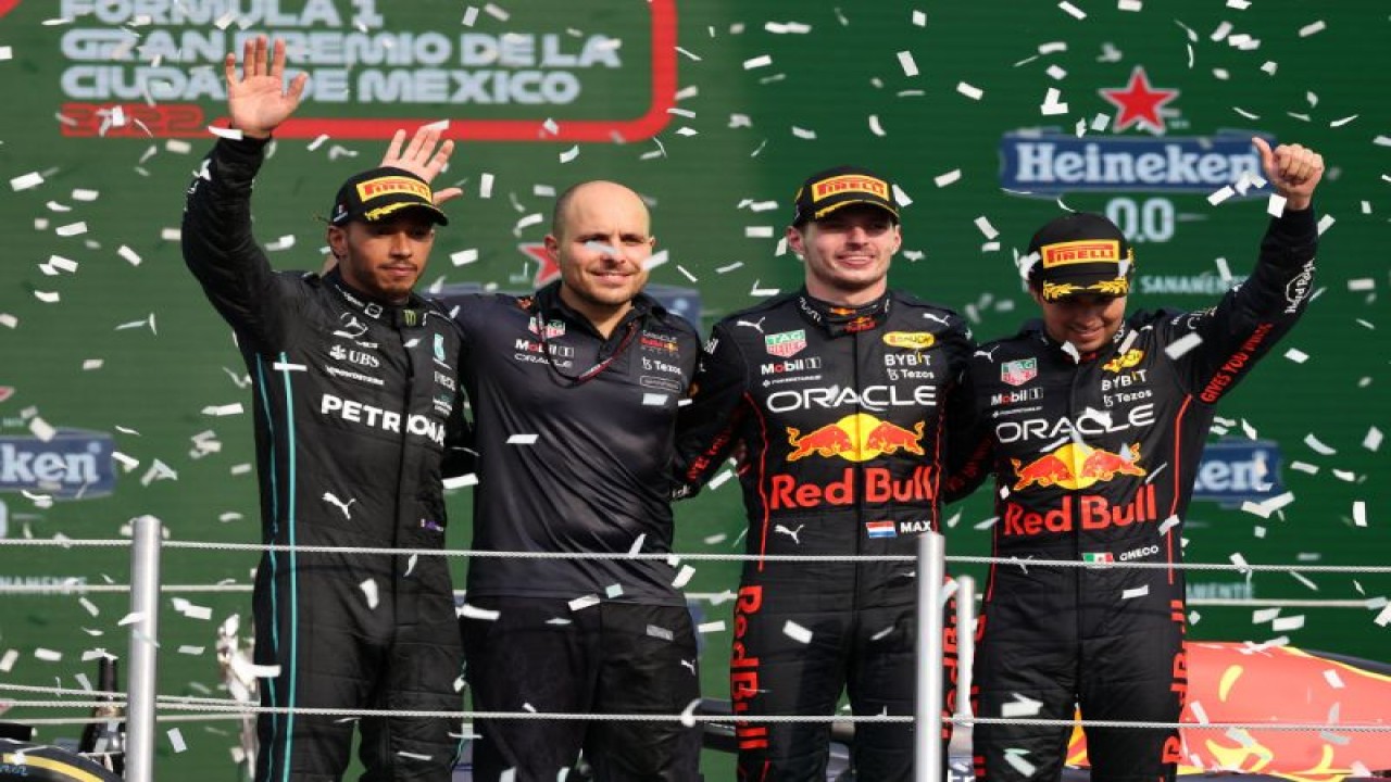 Pebalap tim Red Bull Racing Max Verstappen (kedua kanan) dan Sergio Perez (kanan) dan pebalap Mercedes Lewis Hamilton (kiri) melambaikan tangan di podium balapan Formula 1 di Meksiko, Minggu waktu setempat (30/10/2022). HO/Formula1-Red Bull Racing