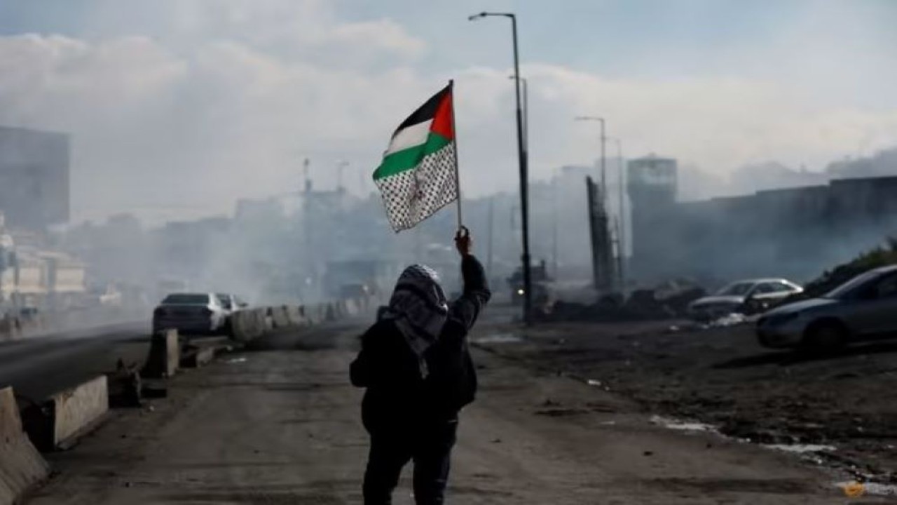 Ilustrasi. Seorang pria berjalan dengan membawa bendera Palestina. (Reuters)