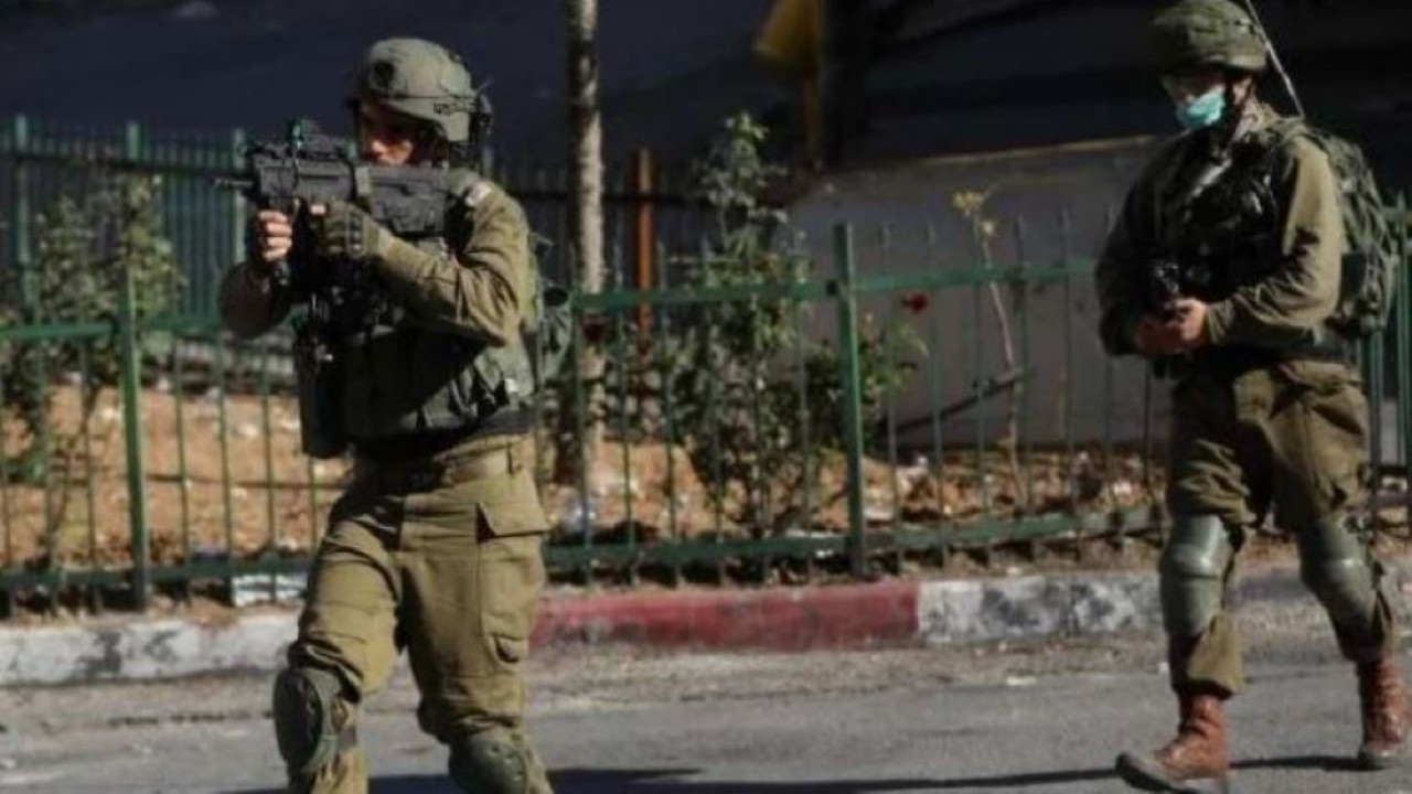 Ilustrasi. Dua tentara Israel bersenjata lengkap bersiap membidik senjata otomatisnya yang diarahkan kepada warga Palestina. (Istimewa/Net)