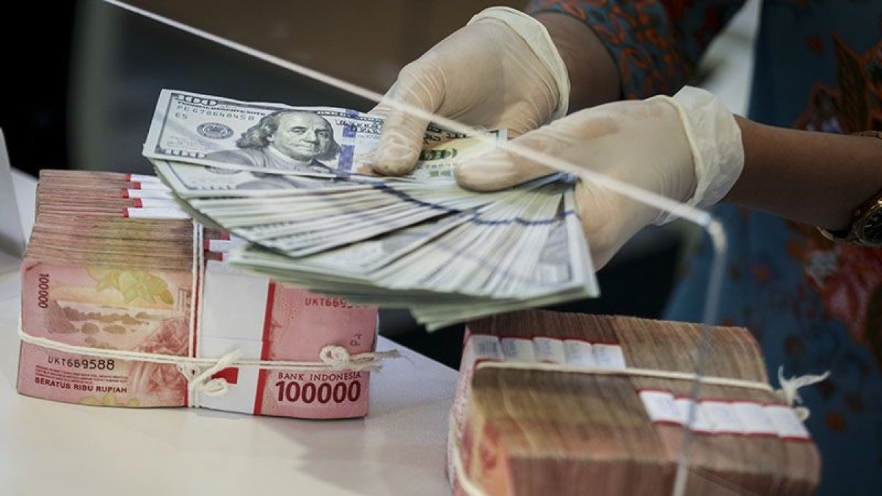 Ilustrasi - Petugas menghitung uang dolar AS di atas tumpukan rupiah pada sebuah cabang bank di Jakarta. ANTARA FOTO/Rivan Awal Lingga/tom/pri.