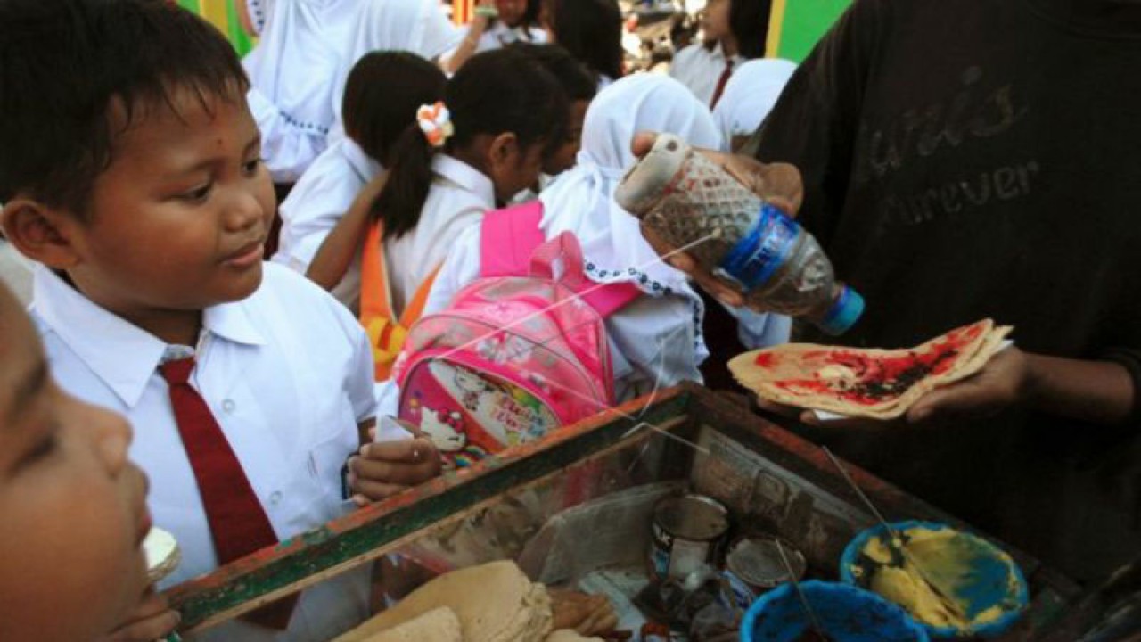 Dua siswa membeli jajanan pinggir jalan pada hari pertama masuk sekolah di SDN Negeri 3, Bugih, Pamekasan, Jatim, Senin (9/7/12). Badan Pengawas Obat dan Makanan (BPOM) mengingatkan masyarakat untuk mewaspadai jajanan anak yang dijajakan karena ditengarai banyak mengandung bahan kimia yang membahayakan kesehatan. FOTO ANTARA/Saiful Bahri/Koz/Spt/12.