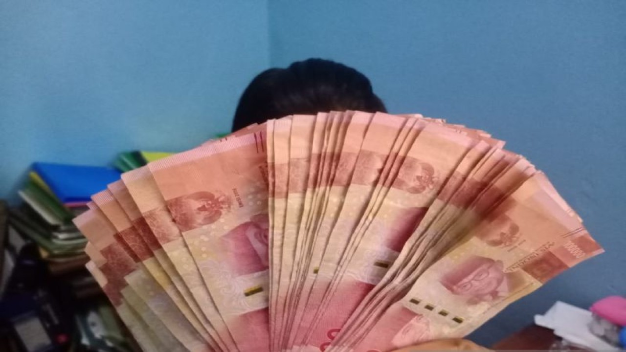 Seorang pegawai kantor meunjukkan uang dengan nominal Rp100 ribu di Kupang, NTT, Selasa (17/01/2023)/ ANTARA/Kornelis Kaha